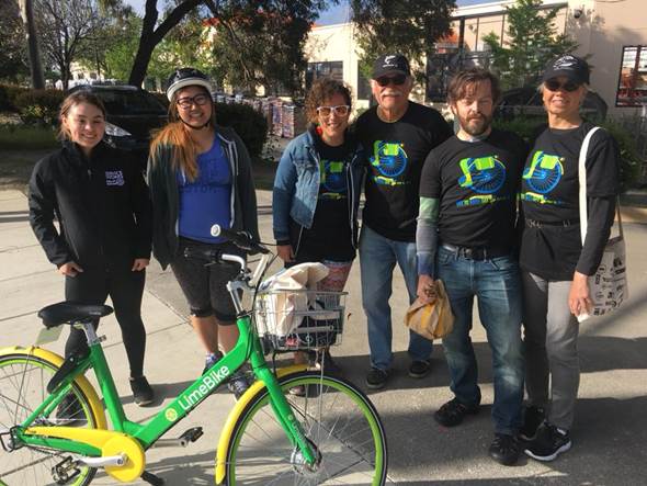 Image may contain: 6 people, people smiling, people standing, bicycle and outdoor