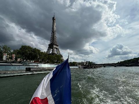 A flag on a boat in front of a tower Description automatically generated