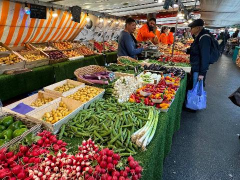 A group of people at a market Description automatically generated