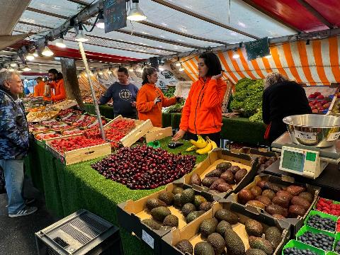 A group of people at a market Description automatically generated