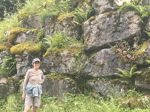 A person standing in front of a rock wall Description automatically generated