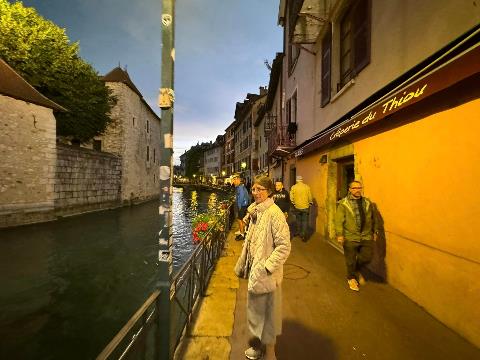 A person walking on a sidewalk next to a canal Description automatically generated
